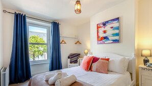 A hotel room with a bed, a window with curtains, a painting on the wall, and a bedside lamp. - 3 Bed in Keswick (oc-89526) (Keswick)