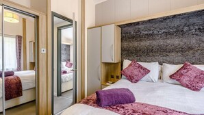 Ein Hotelzimmer mit einem Bett, einem Kleiderschrank, einem Spiegel und einer Tür zu einem anderen Raum.