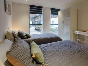 A bedroom with two beds, a desk, and a view of the outside. - 2 Bed in Porthcawl (oc-89696) (Porthcawl)