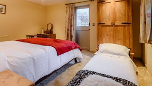 Une chambre avec deux lits, une armoire en bois, une commode, un miroir et un lustre.