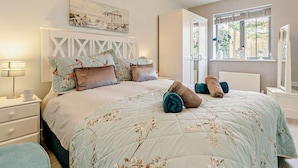 Une chambre à coucher avec un lit, une table de chevet, une lampe, une fenêtre et une porte.