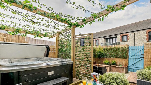 Un bain à remous, des sièges extérieurs et une table avec des fruits et des boissons, le tout dans un cadre de jardin.