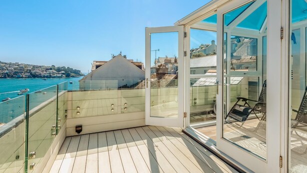 Ein Balkon mit Glasgeländer mit Blick auf die Küste.