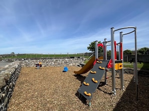 Ein Spielplatz mit Rutsche, Klettergeräten und Fallschutzbelag.