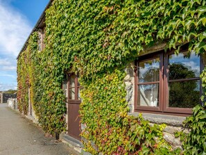 Ein Gebäude aus Stein mit traditioneller Gestaltung, das ein Fenster mit Holzrahmen und eine Tür zeigt.