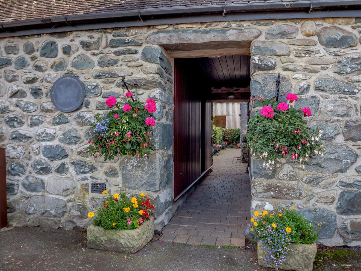 A stone building with a narrow entrance, stone walls, and hanging flower baskets.