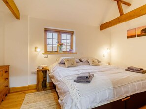Une chambre à coucher avec un lit, une fenêtre, une table de chevet, une commode et un tapis.