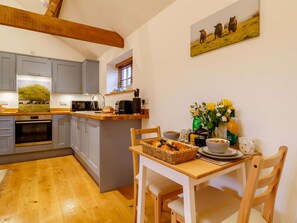 Eine moderne Küche mit grauen Schränken, einer Holzdecke und einem Essbereich mit gedecktem Tisch für das Frühstück.