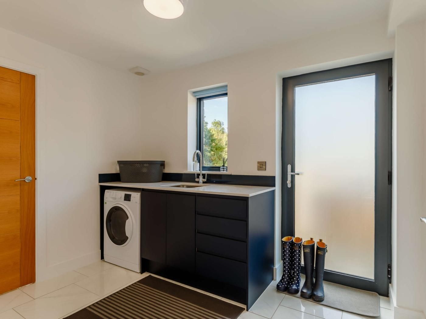 A modern kitchen with a washing machine, a sink, and a window.