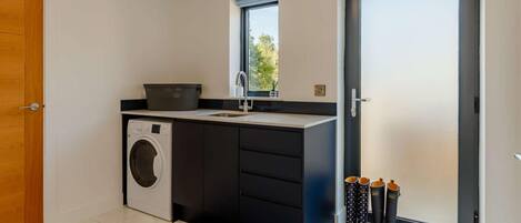 A modern kitchen with a washing machine, a sink, and a window.