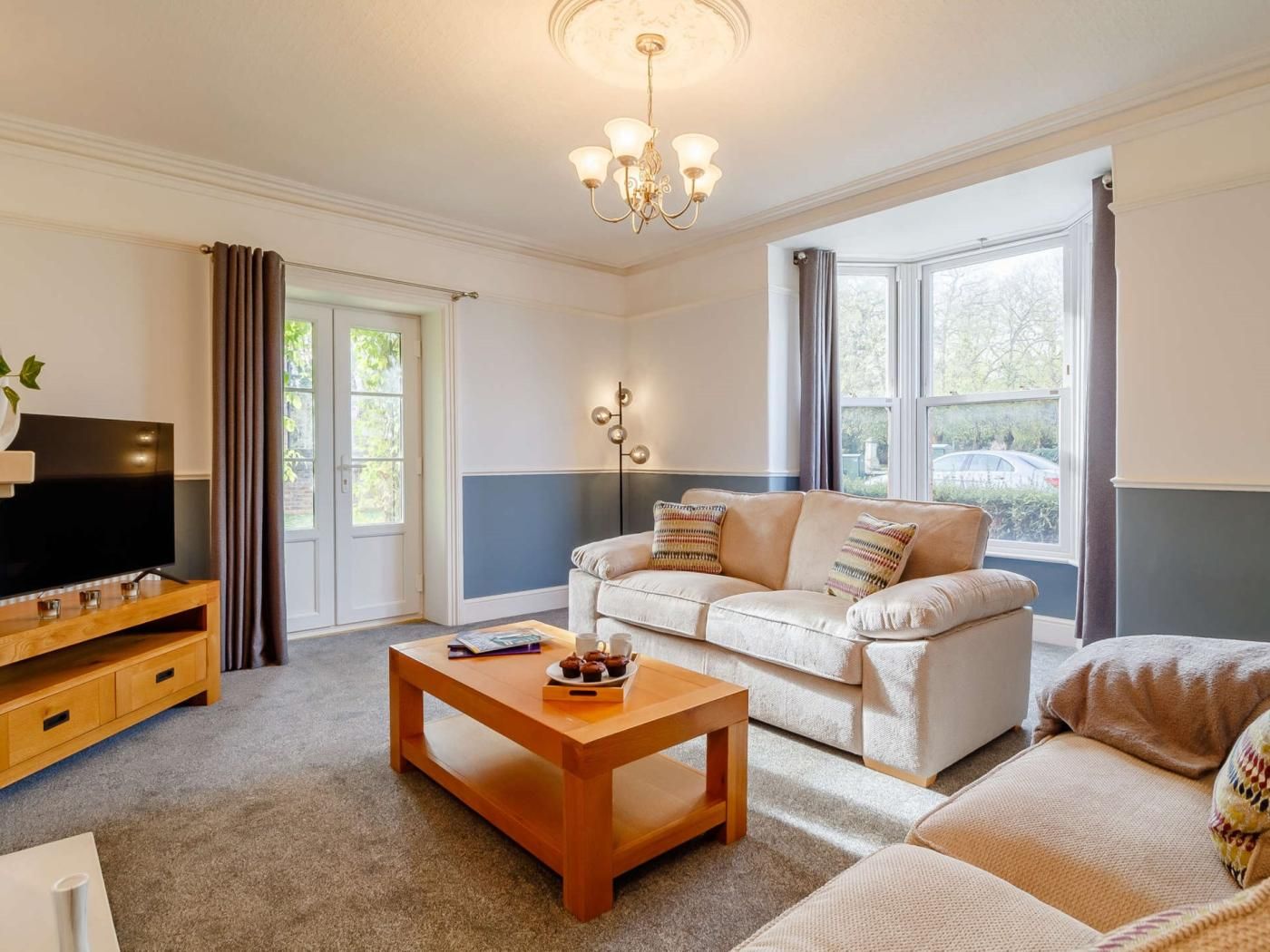 A living room with a sofa, a coffee table, a TV, and a window with curtains.