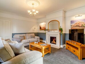 A living room with a fireplace, a sofa, a coffee table, and a television. - 5 Bed in Wisbech (oc-90134) (Wisbech)