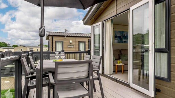 En terrass med ett bord och stolar, en skjutdörr i glas och en byggnad i bakgrunden.