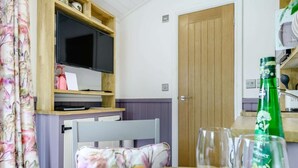 Ein Zimmer mit Fernseher, Holzregal, Tür und Tisch mit Früchten und Gläsern.