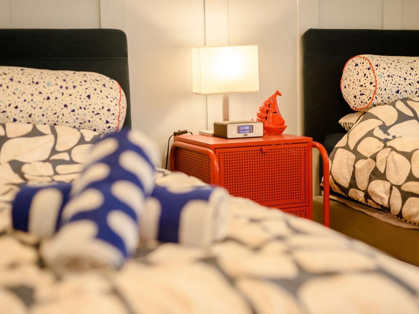 A hotel room with a bed, a nightstand with a lamp, and a digital clock.