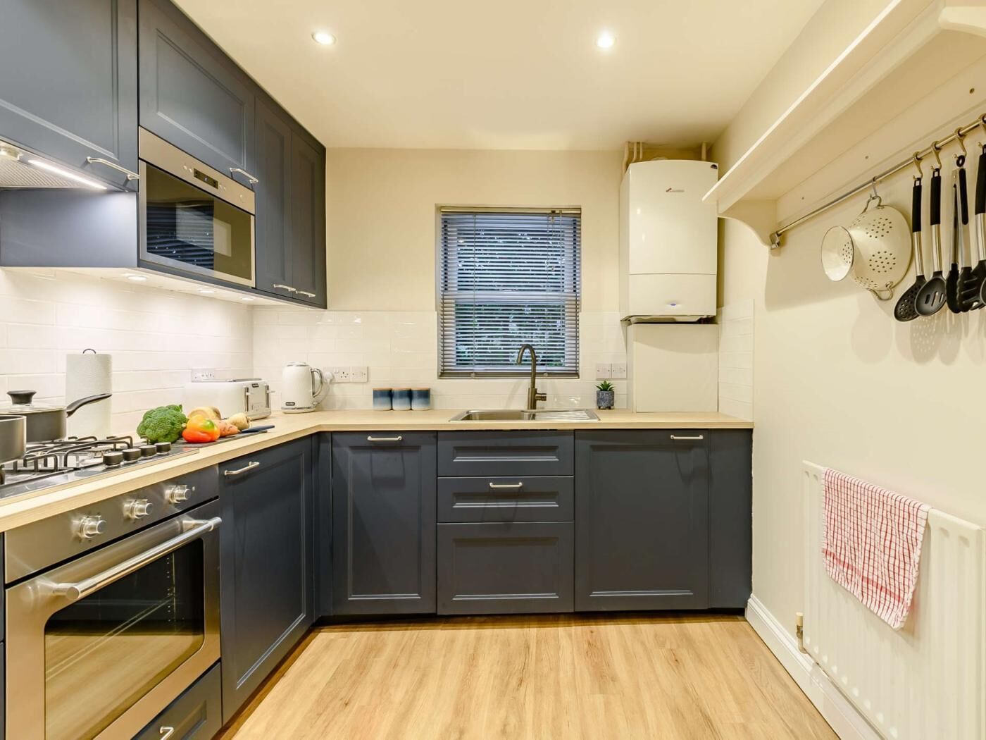 Una cucina moderna con mobili scuri, forno integrato, piano cottura e finestra con persiane.