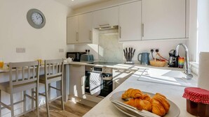 Una cucina moderna con zona pranzo, un orologio al muro e una colazione con cornetti.