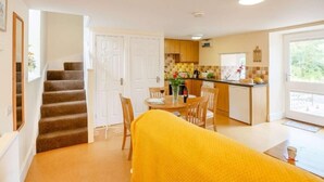 A compact living space with a staircase, a dining area, and a kitchen. - 1 Bed in Bala (oc-89369) (Llandderfel)