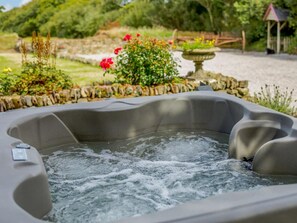 Ein Whirlpool, umgeben von einer Steinmauer und einem Garten.