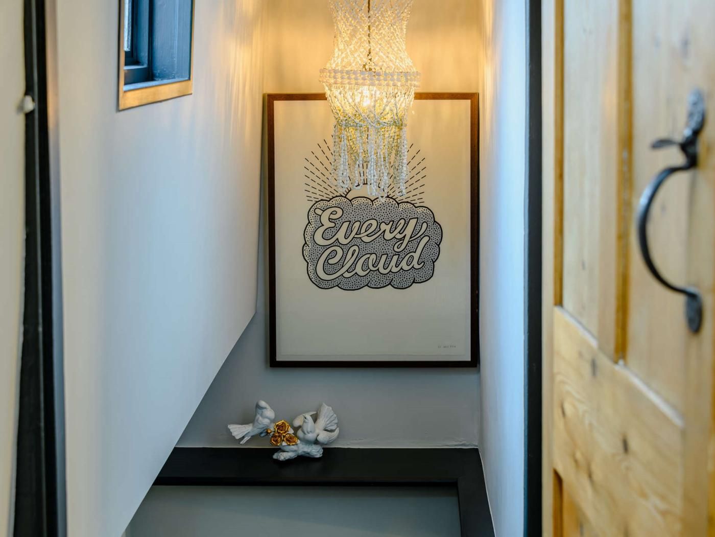 A framed artwork with the text 'Every Cloud' and a chandelier above it.