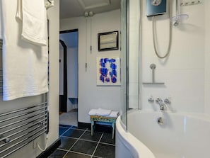 A bathroom with a bathtub, a shower, and a small bench.