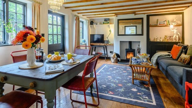 A cozy living room with a fireplace, a dining area with a table set for two, and a comfortable seating area with a sofa. - 1 Bed in Bridport (oc-89687) (Bridport)