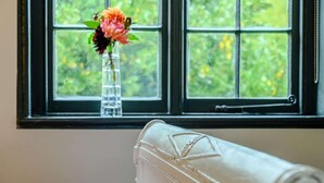 A room with a window, a white bench, and a vase with flowers. - 1 Bed in Bridport (oc-89687) (Bridport)