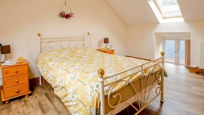 A bedroom with a bed, a nightstand, a dresser, a lamp, a window, and a skylight. - 1 Bed in Bala (oc-89368) (Llandderfel)