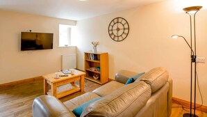 A living room with a sofa, a coffee table, a TV, a bookshelf, and a clock on the wall. - 1 Bed in Bala (oc-89368) (Llandderfel)