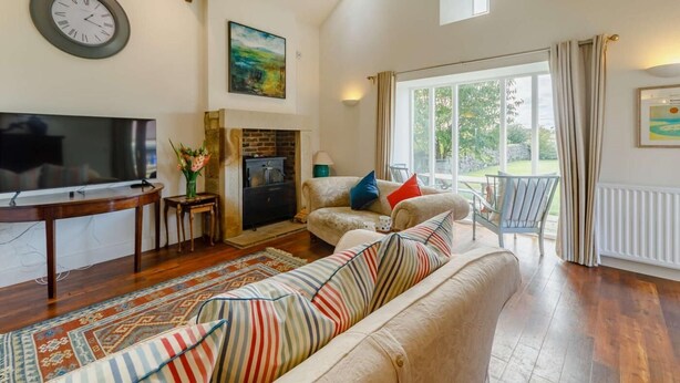 A spacious living room with a fireplace, a television, and a large window. - 3 Bed in Belford (oc-89518) (Belford)