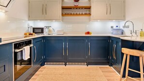 Une cuisine moderne avec des meubles bleus, un four à micro-ondes, un grille-pain et un boîtier à pain.