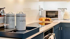 Une cuisine équipée d’une machine à café, de boîtes à thé, d’un four à micro-ondes et d’un grille-pain.