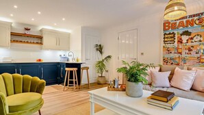 Une cuisine moderne avec un plan de travail blanc, des armoires en bois et un luminaire suspendu.