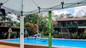Una piscina con una marquesina, un flotador salvavidas y una escalera que lleva a un edificio.
