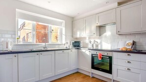 A modern kitchen with white cabinets, a window, a microwave, and a kettle. - 3 Bed in Newport (oc-90245) (Newport)