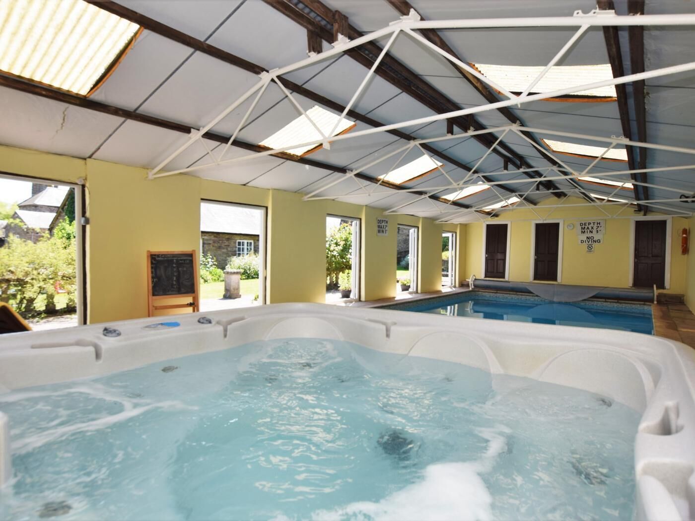 A hot tub with a view of the outdoors, a chalkboard, and a sign indicating a depth limit.