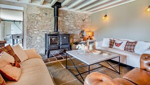 Ein gemütliches Wohnzimmer mit Steinwand, einer Couch, einem Couchtisch und einem Kamin.