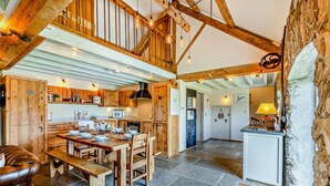 Ein rustikales Interieur mit freiliegenden Holzbalken, einem steinbelagten Boden, einem Essplatz aus Holz und einer Steinwand.