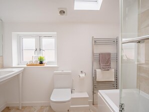 Une salle de bain moderne dotée d’une lucarne, de toilettes, d’une douche et d’un porte-serviettes.