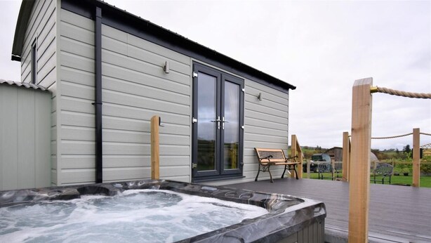 Un espace bien-être comprenant un jacuzzi, une terrasse en bois et un banc.