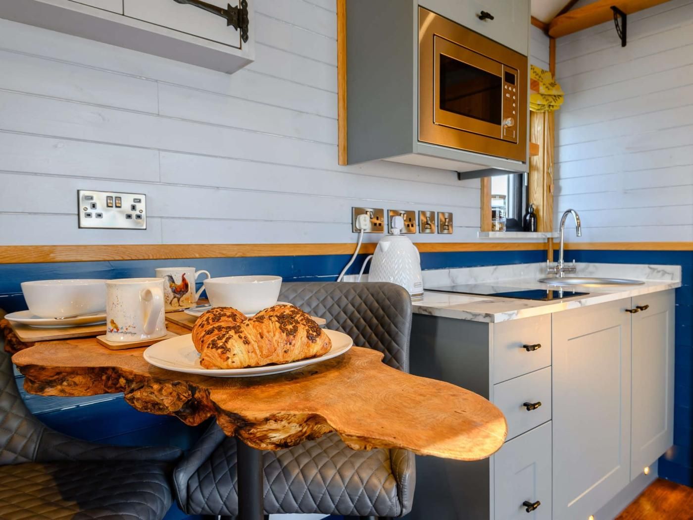 Une cuisine moderne avec une table en bois, un four à micro-ondes et un évier.