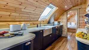 Cozinha moderna com teto de madeira, um claraboia e vista para um quarto.