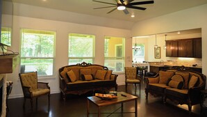 A spacious living room with a large sofa, two armchairs, a coffee table, and a ceiling fan.