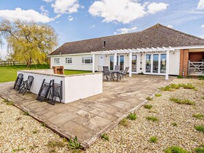 Ein Haus mit Terrasse, Sitzgelegenheiten im Freien und einem Garten.