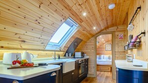 Een compacte, moderne keuken met dakraam, houten wanden en een gezellig slaapgedeelte.