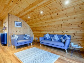 A cozy room with wooden walls and ceiling, two sofas with plaid cushions, a small table with a cup, and a framed picture on the wall. - 2 Bed in Rhayader (oc-90274) (Saint Harmon)