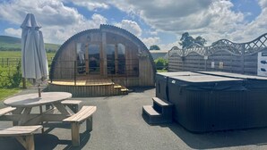 Eine Holzkonstruktion mit Glasfassade, Whirlpool und Picknicktischen.
