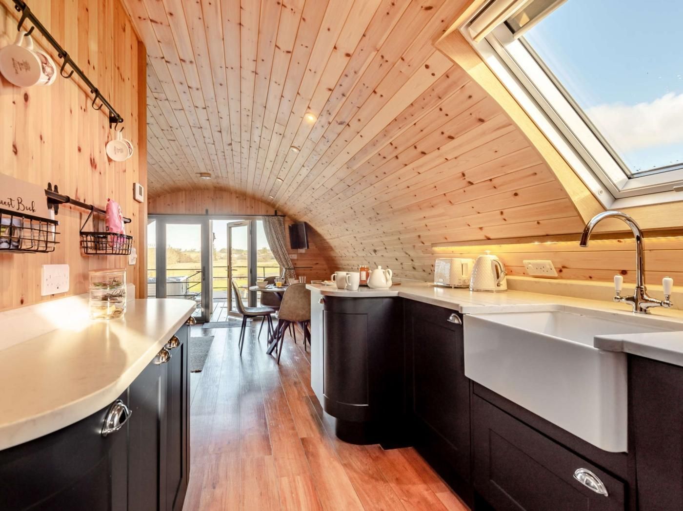 A compact kitchen with a wooden ceiling, a skylight, and a view of the outdoors.
