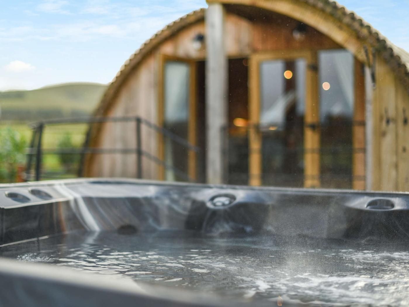 Ein Whirlpool mit einer Holzhütte im Hintergrund.