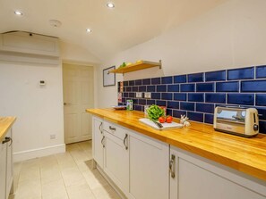A kitchen with a wooden countertop, a toaster, and a blue-tiled backsplash.
